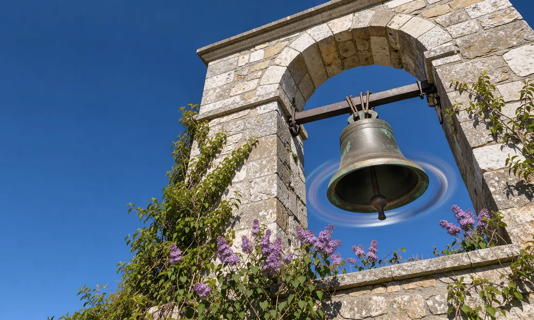 A bronze bell swings inside an open stone tower, its rim tracing overlapping arcs.
